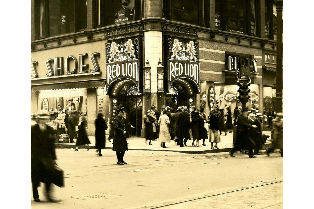 Pedestrians outside a corner storefront with Red Lion signs above the entrance.