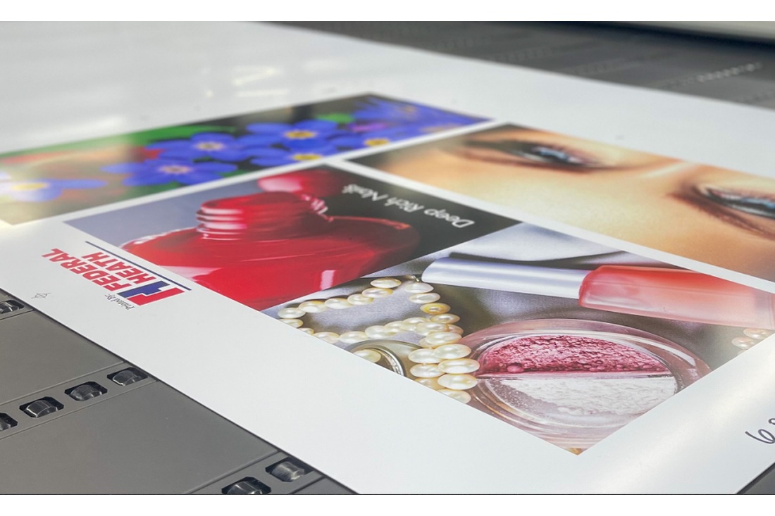 Large-format printer producing a sheet of colorful promotional graphics.