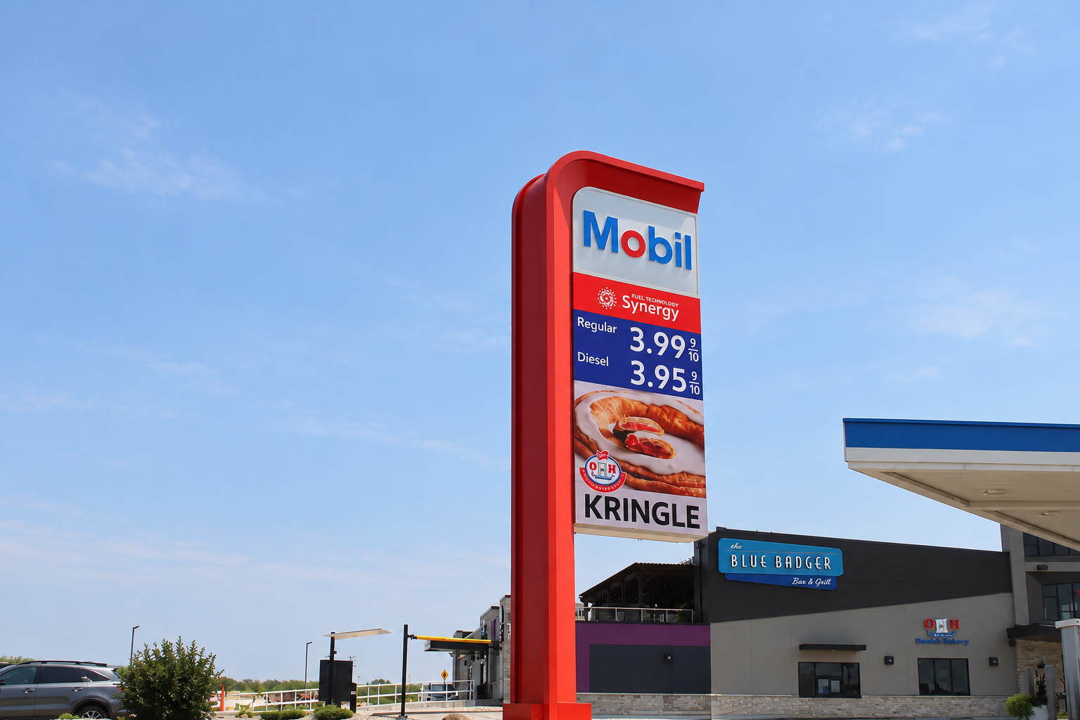 Illuminated Exxon roadside pylon sign at dusk with digital fuel prices and an electronic promotional display.