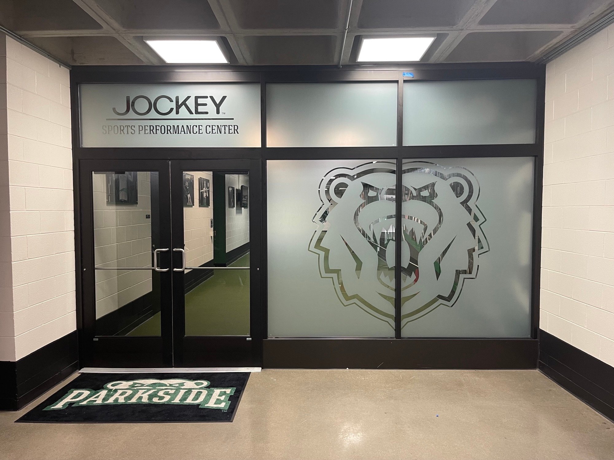 Frosted window graphics with the Parkside bear mascot and Jockey Sports Performance Center entrance lettering.