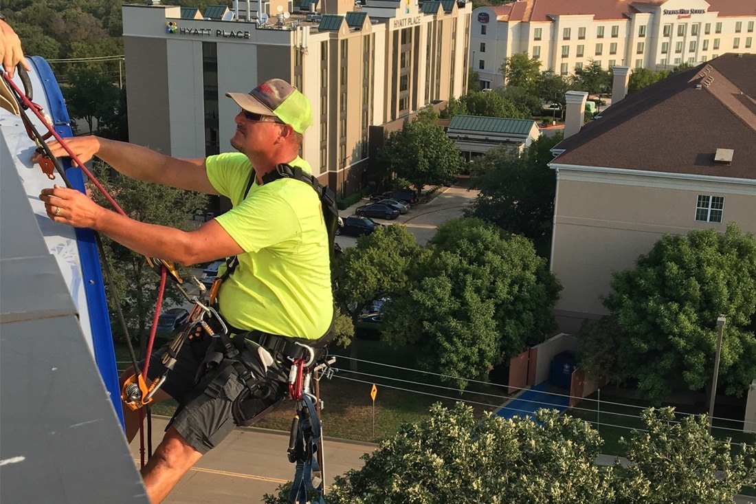 Man rappelling for hilton sign maintenance