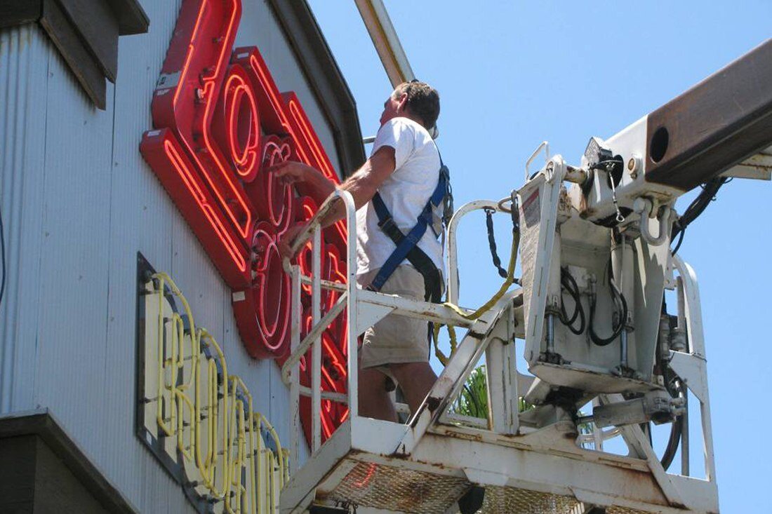 Man repairing neon open face sign