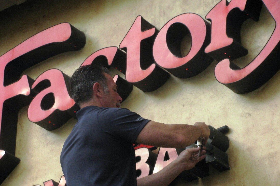 Man doing maintenance on cheesecake factory channel letters