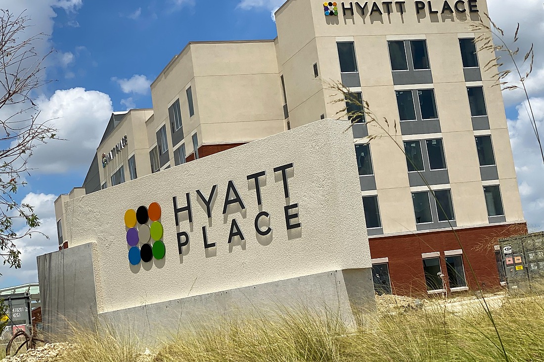 Hyatt Place monument sign with a multicolored logo and dimensional black lettering in front of a hotel with matching building signage.