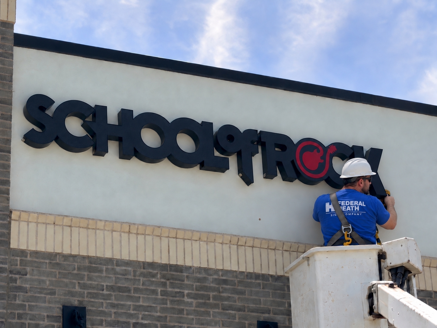 Technician repairing School of Rock sign