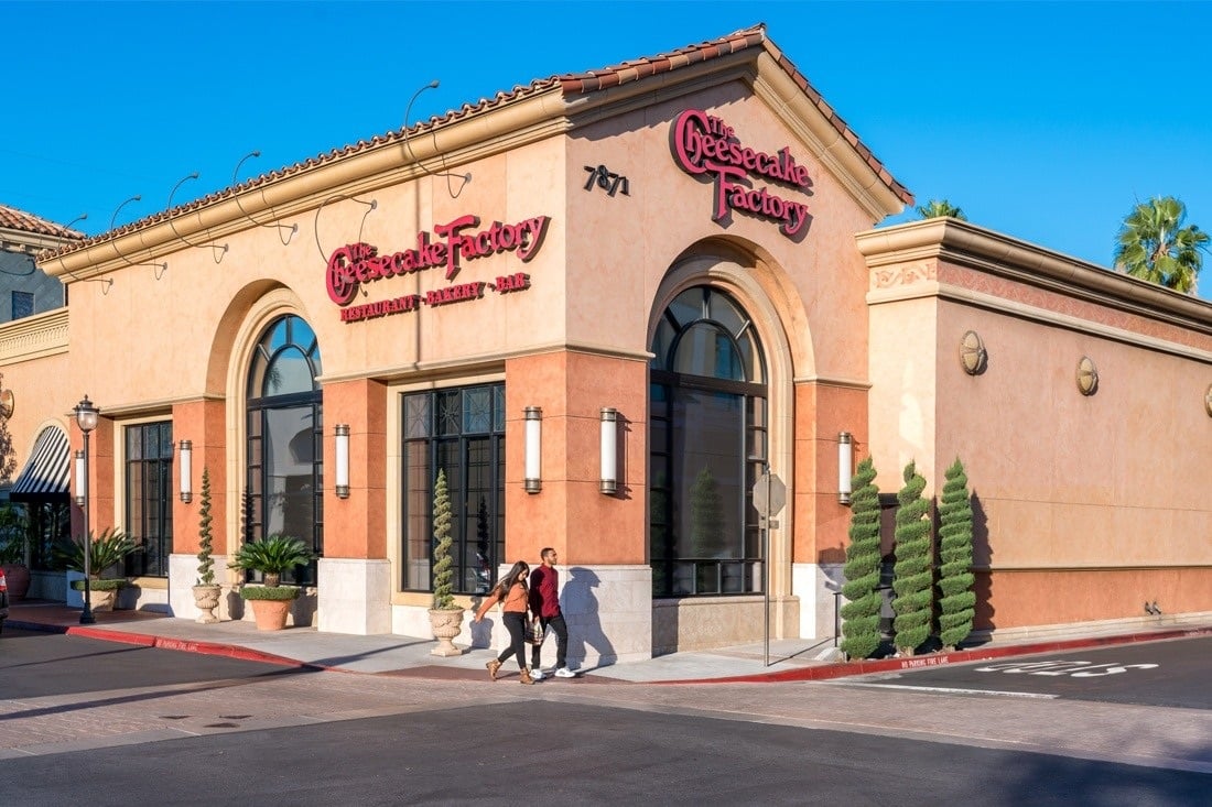The Cheesecake Factory restaurant with burgundy wall lettering above arched windows and entrances.