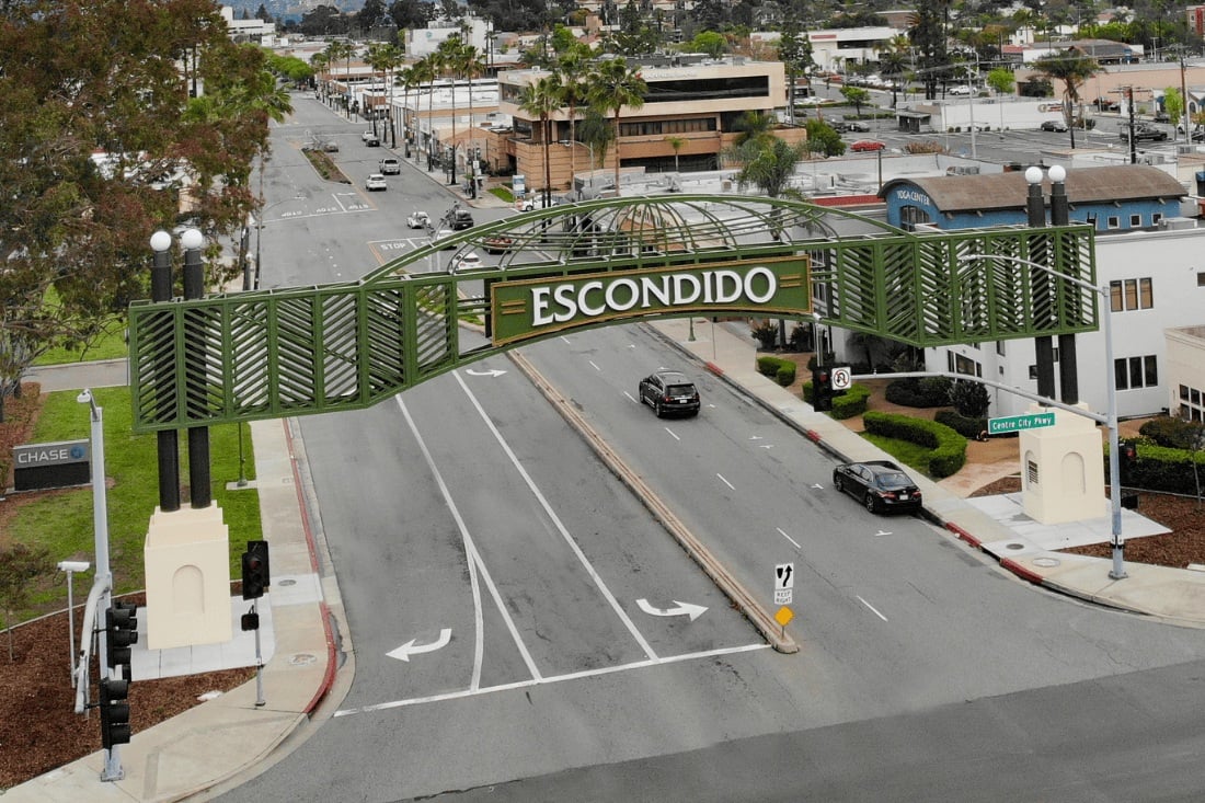 Green Escondido archway sign spanning a downtown street between decorative support columns.