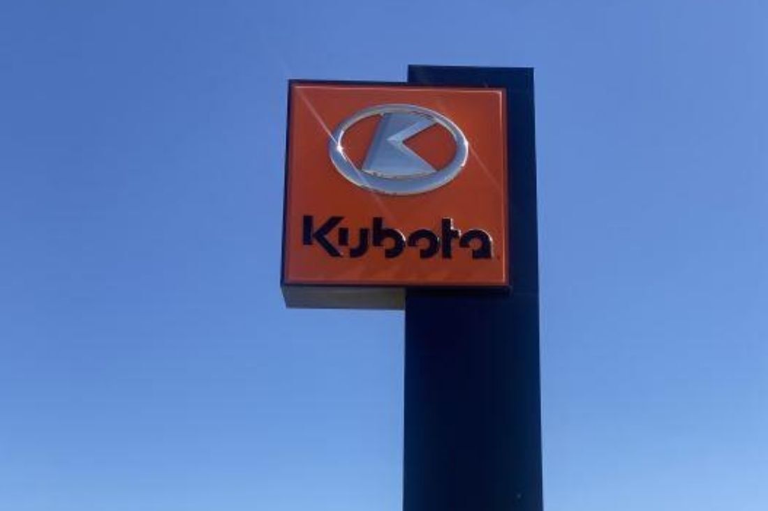 Illuminated orange Kubota pylon sign against a clear sky.