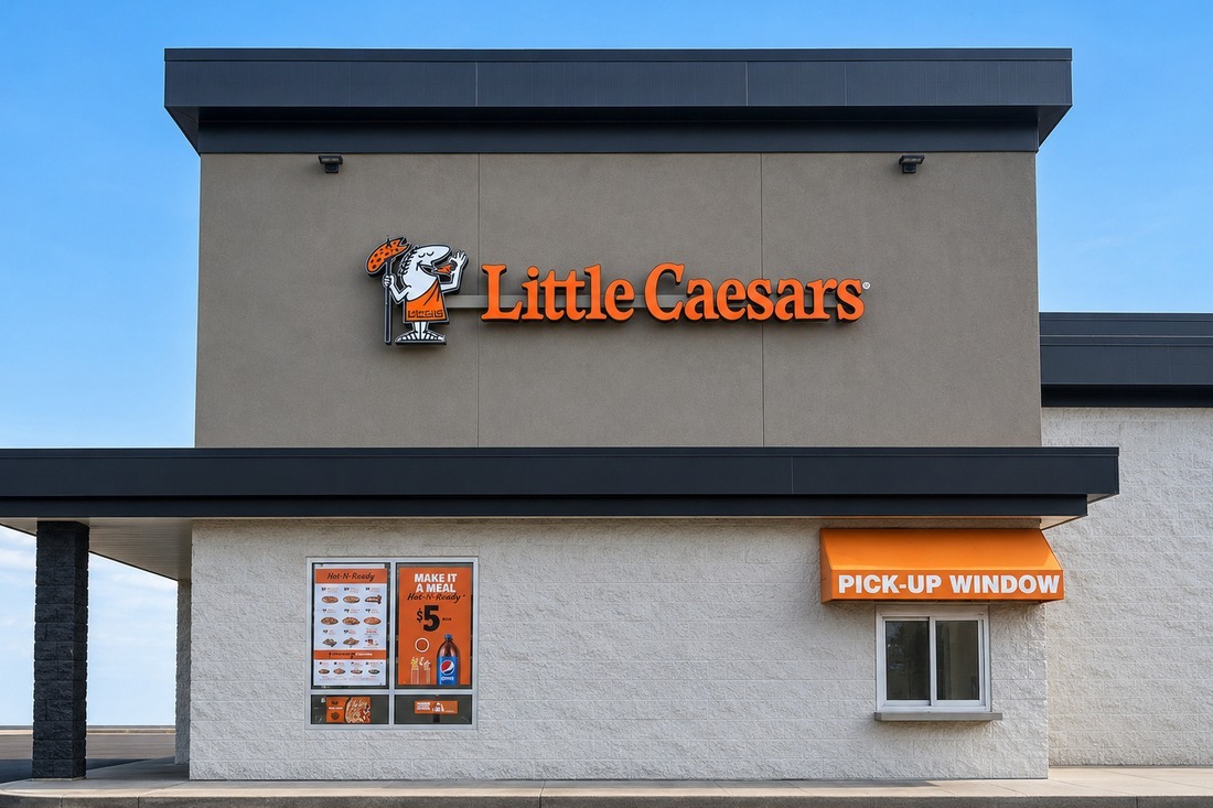 Little Caesars restaurant exterior with orange logo signage and a branded pickup window awning.