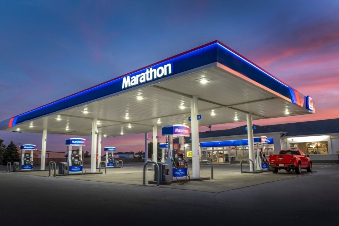 Illuminated Marathon fuel canopy with blue and red trim above gas pumps at dusk.