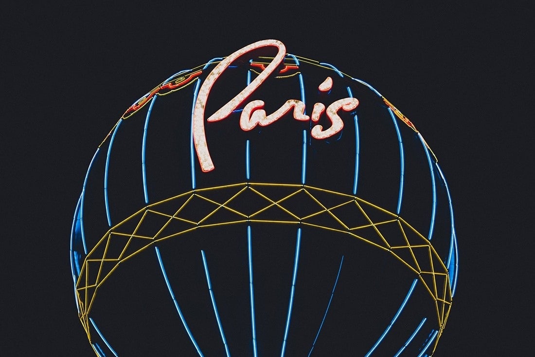 Close-up of the Paris Las Vegas balloon sign with illuminated script and blue and gold outlines at night.