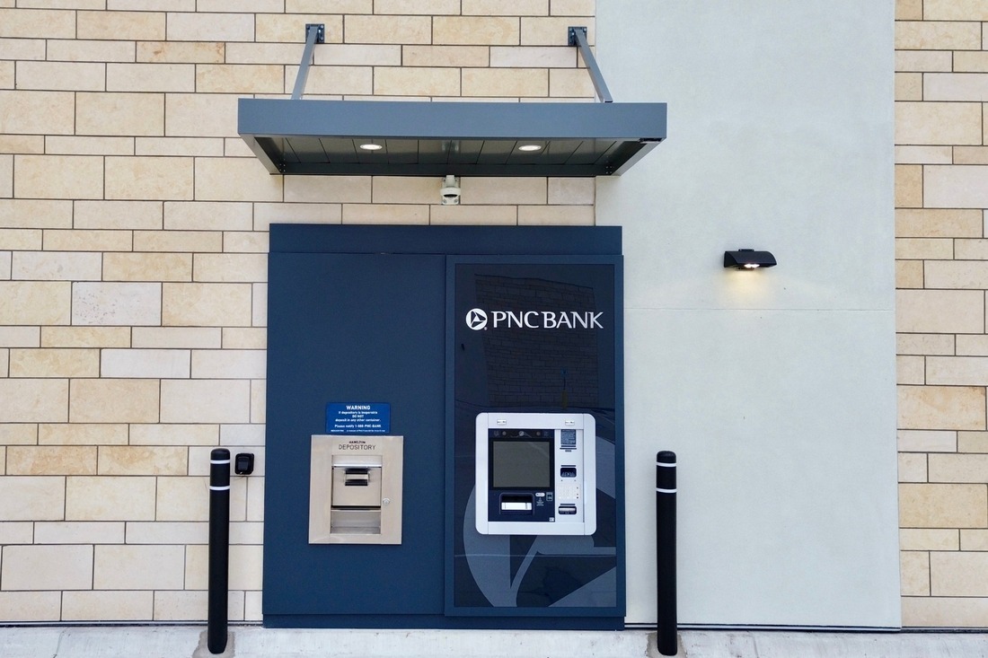 PNC Bank ATM surround with branded graphics and adjacent deposit box beneath an exterior canopy.