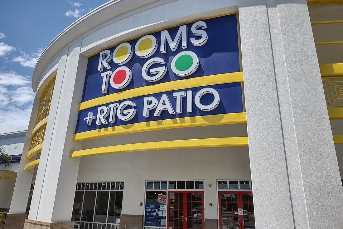 Large Rooms To Go and RTG Patio signs on a curved retail building facade.