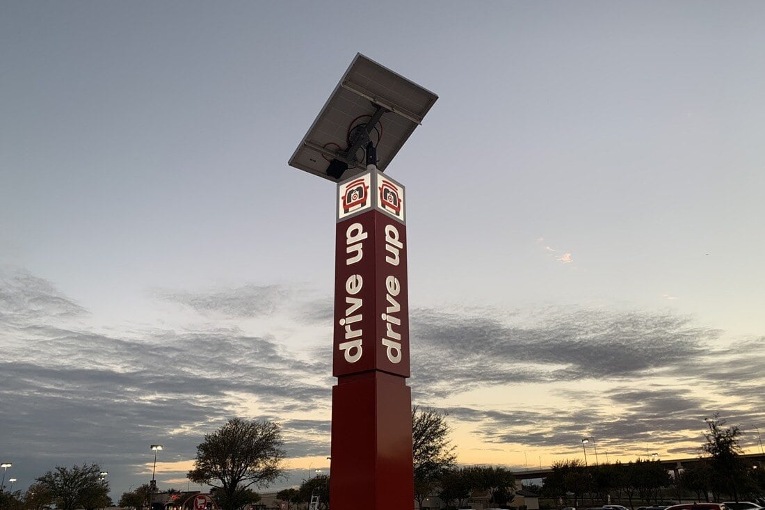 Red Target Drive Up pickup sign topped by a solar panel against an evening sky.