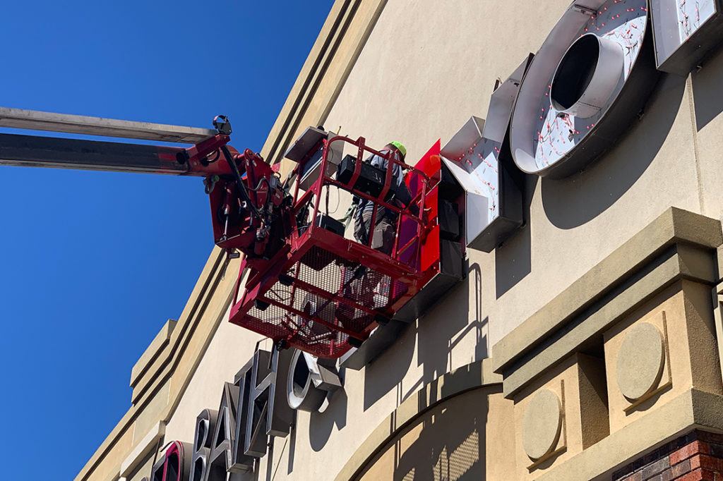 worker performing maintenance on bed bath and beyond sign